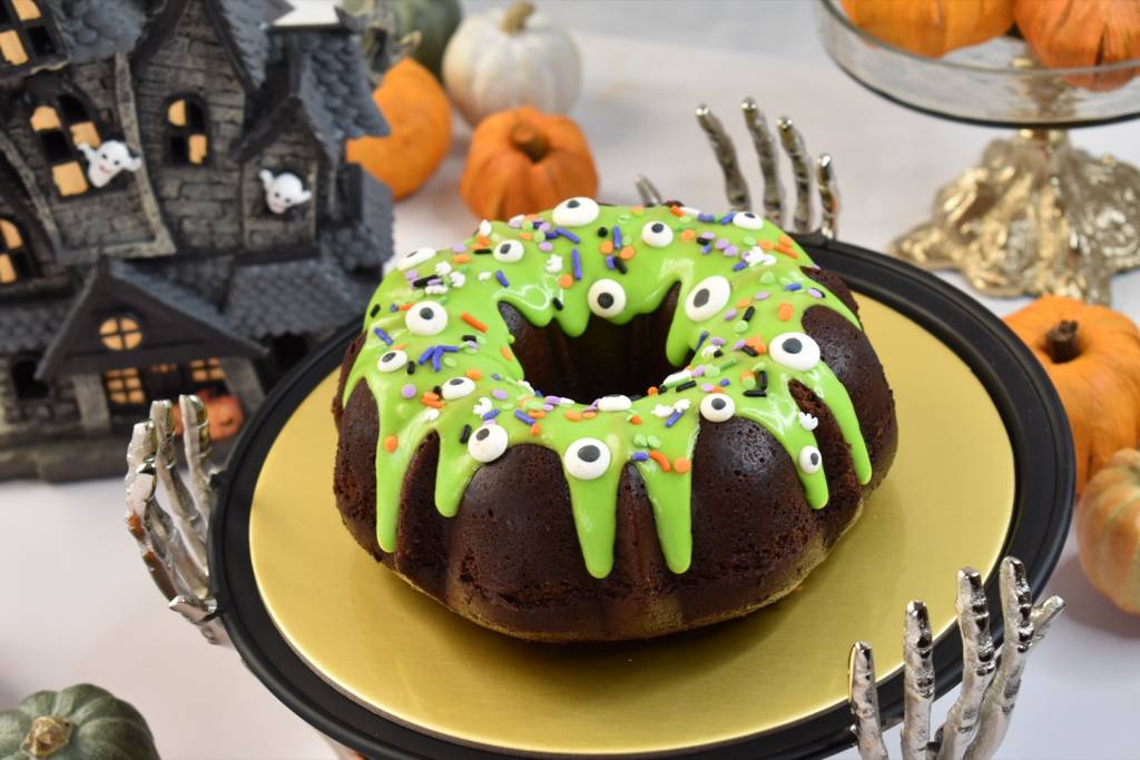 Halloween dessert table with green slime bundt cake centerpiece and spooky decorations