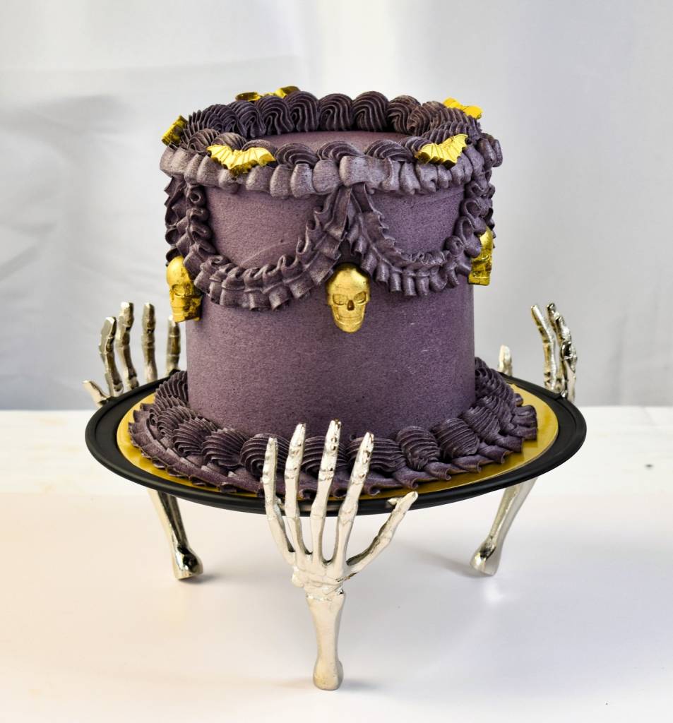 Elegant purple Halloween cake with gold details on decorative stand